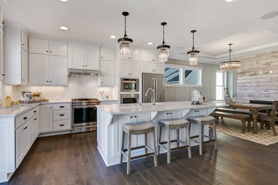 Example of a large transitional l-shaped dark wood floor and brown floor open concept kitchen design in Minneapolis with an undermount sink, shaker cabinets, white cabinets, quartz countertops, white backsplash, mosaic tile backsplash, stainless steel appliances and an island
