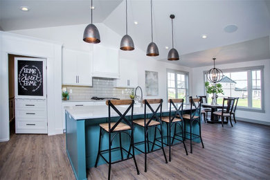Example of a large classic l-shaped vinyl floor and brown floor eat-in kitchen design in Other with a farmhouse sink, shaker cabinets, white cabinets, quartz countertops, gray backsplash, glass tile backsplash, stainless steel appliances and an island