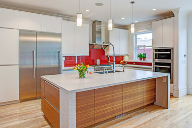 Mid-sized trendy l-shaped light wood floor and brown floor kitchen photo in San Francisco with an undermount sink, flat-panel cabinets, white cabinets, marble countertops, red backsplash, glass sheet backsplash, stainless steel appliances and an island