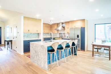 Inspiration for a mid-sized contemporary l-shaped light wood floor and beige floor open concept kitchen remodel in New York with an undermount sink, flat-panel cabinets, light wood cabinets, marble countertops, white backsplash, marble backsplash, stainless steel appliances, an island and white countertops