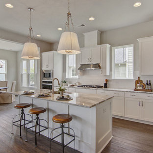 Transitional eat-in kitchen photos - Transitional l-shaped medium tone wood floor and brown floor eat-in kitchen photo in Charleston with an undermount sink, shaker cabinets, white cabinets, white backsplash, subway tile backsplash, stainless steel appliances, an island and gray countertops
