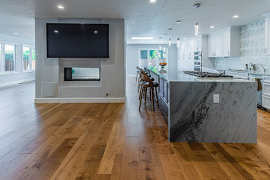 Huge single-wall light wood floor and brown floor eat-in kitchen photo in San Francisco with an undermount sink, shaker cabinets, white cabinets, quartzite countertops, gray backsplash, mosaic tile backsplash, stainless steel appliances, an island and gray countertops