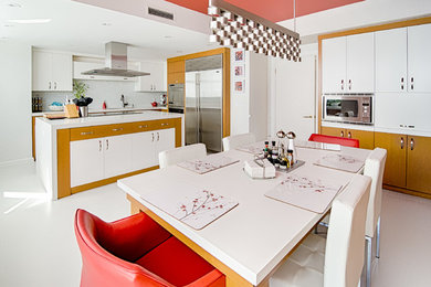 Modelo de cocina comedor contemporánea con armarios con paneles lisos, puertas de armario blancas, salpicadero blanco, salpicadero de azulejos en listel y electrodomésticos de acero inoxidable