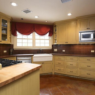 Ejemplo de cocina comedor en U, tradicional, de tamaño medio, con armarios con rebordes decorativos, puertas de armario beige, salpicadero marrón, salpicadero de azulejos de porcelana, electrodomésticos de acero inoxidable, suelo de baldosas de porcelana, suelo marrón, encimera de cobre y encimeras naranjas