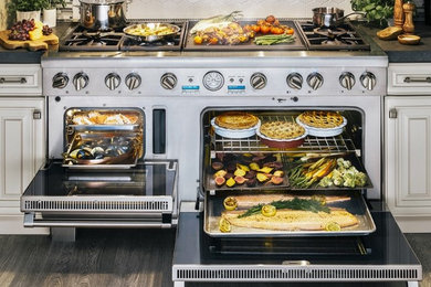 Réalisation d'une cuisine ouverte design en L de taille moyenne avec un placard avec porte à panneau surélevé, des portes de placard blanches, un plan de travail en stéatite, une crédence multicolore, une crédence en carreau briquette, un électroménager en acier inoxydable, parquet clair, îlot et un sol marron.