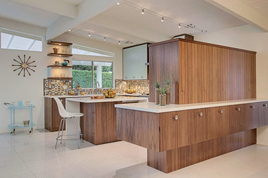 Mid-century modern travertine floor eat-in kitchen photo in Vancouver with a drop-in sink, flat-panel cabinets, medium tone wood cabinets, quartz countertops, multicolored backsplash, glass tile backsplash, stainless steel appliances and an island