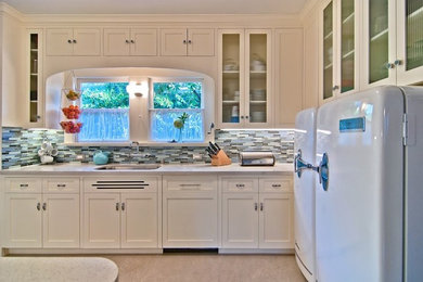 Modelo de cocina ecléctica con fregadero bajoencimera, armarios estilo shaker, puertas de armario blancas, salpicadero multicolor y electrodomésticos blancos