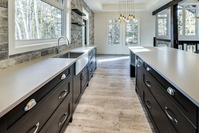 Open concept kitchen - large craftsman l-shaped vinyl floor open concept kitchen idea in Calgary with a farmhouse sink, shaker cabinets, black cabinets, quartzite countertops, gray backsplash, ceramic backsplash, stainless steel appliances and an island