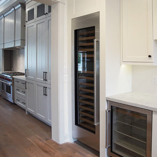 Large traditional l-shaped eat-in kitchen in Phoenix with a farmhouse sink, louvered cabinets, grey cabinets, quartzite benchtops, white splashback, stone slab splashback, white appliances, dark hardwood floors, with island and brown floor.