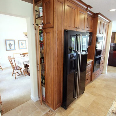Inspiration for a mid-sized transitional u-shaped porcelain tile eat-in kitchen remodel in Orange County with a double-bowl sink, recessed-panel cabinets, medium tone wood cabinets, granite countertops, brown backsplash, stone tile backsplash, black appliances and a peninsula