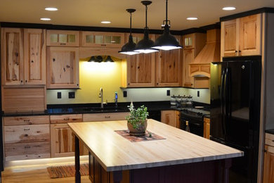 Eat-in kitchen - mid-sized transitional l-shaped eat-in kitchen idea in Other with an undermount sink, recessed-panel cabinets, light wood cabinets, solid surface countertops, black appliances and an island