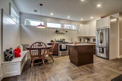 Small danish l-shaped vinyl floor eat-in kitchen photo in New York with an undermount sink, shaker cabinets, dark wood cabinets, solid surface countertops, white backsplash, ceramic backsplash, stainless steel appliances and an island