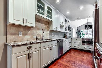 Enclosed kitchen - mid-sized transitional galley medium tone wood floor enclosed kitchen idea in Atlanta with an undermount sink, raised-panel cabinets, white cabinets, stone tile backsplash, paneled appliances and no island