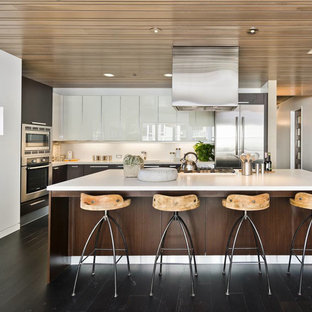 This is an example of a mid-sized contemporary l-shaped open plan kitchen in San Francisco with stainless steel appliances, an integrated sink, flat-panel cabinets, dark wood cabinets, quartz benchtops, white splashback, dark hardwood floors and with island.