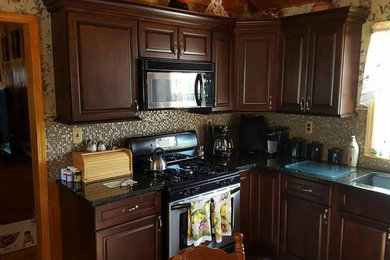 Photo of a kitchen in Boston with raised-panel cabinets, dark wood cabinets, granite worktops and glass sheet splashback.