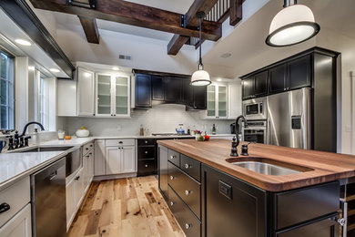 Open concept kitchen - large transitional u-shaped light wood floor open concept kitchen idea in New York with a farmhouse sink, recessed-panel cabinets, black cabinets, quartz countertops, white backsplash, glass tile backsplash, stainless steel appliances and an island
