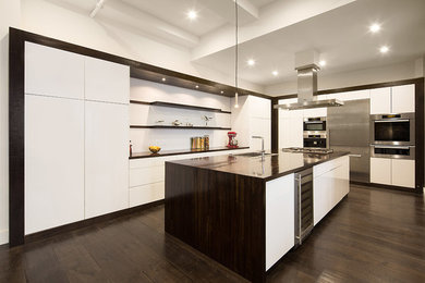 Photo of an expansive contemporary kitchen in New York with flat-panel cabinets, white cabinets, wood worktops, stainless steel appliances, dark hardwood flooring and an island.