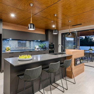 Design ideas for a large contemporary galley open plan kitchen in Canberra - Queanbeyan with flat-panel cabinets, black cabinets, glass sheet splashback, black appliances, light hardwood floors, with island, white floor and grey benchtop.