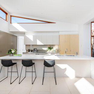 Inspiration for a contemporary galley open plan kitchen in Canberra - Queanbeyan with an undermount sink, flat-panel cabinets, beige cabinets, beige splashback, panelled appliances, with island, beige floor and white benchtop.