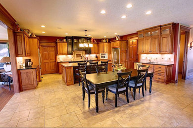 Large elegant l-shaped concrete floor and beige floor eat-in kitchen photo in Other with an undermount sink, raised-panel cabinets, dark wood cabinets, granite countertops, beige backsplash, ceramic backsplash, stainless steel appliances and an island
