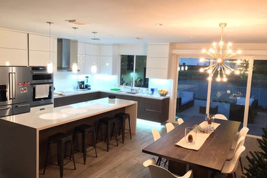 Eat-in kitchen - large contemporary l-shaped porcelain tile and brown floor eat-in kitchen idea in Miami with an undermount sink, flat-panel cabinets, white cabinets, quartzite countertops, white backsplash, glass tile backsplash, stainless steel appliances and an island