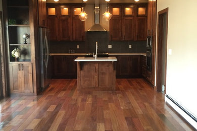Inspiration for a mid-sized rustic u-shaped medium tone wood floor and brown floor open concept kitchen remodel in Denver with shaker cabinets, medium tone wood cabinets, an island, white countertops, an undermount sink, gray backsplash, porcelain backsplash and stainless steel appliances