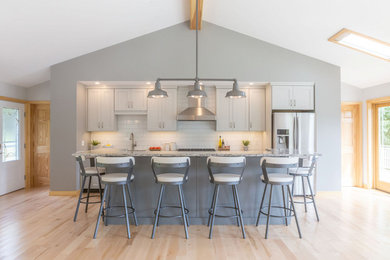 Large transitional galley light wood floor and beige floor eat-in kitchen photo in Burlington with a farmhouse sink, shaker cabinets, gray cabinets, quartz countertops, white backsplash, subway tile backsplash, stainless steel appliances, an island and gray countertops