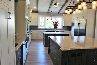 Eat-in kitchen - large transitional u-shaped brown floor and medium tone wood floor eat-in kitchen idea in Other with shaker cabinets, white cabinets, quartzite countertops, multicolored backsplash, glass tile backsplash, stainless steel appliances, two islands, an undermount sink and brown countertops