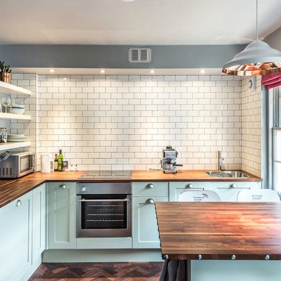 Eat-in kitchen - traditional dark wood floor eat-in kitchen idea in Edinburgh with a peninsula, shaker cabinets, blue cabinets, wood countertops, white backsplash and subway tile backsplash