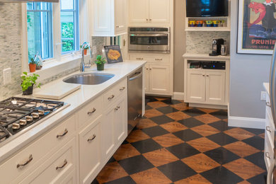 ニューヨークにあるお手頃価格の小さなトランジショナルスタイルのおしゃれなキッチン (アンダーカウンターシンク、フラットパネル扉のキャビネット、白いキャビネット、クオーツストーンカウンター、緑のキッチンパネル、大理石のキッチンパネル、シルバーの調理設備、無垢フローリング、茶色い床、白いキッチンカウンター) の写真
