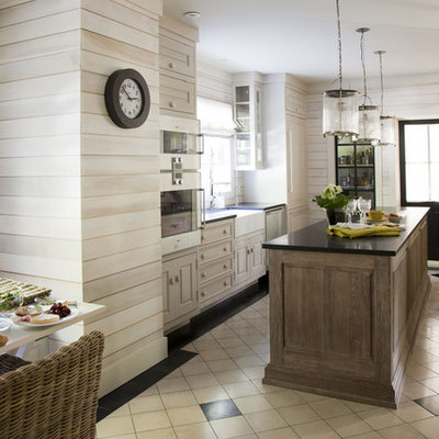 Example of a trendy eat-in kitchen design in Montreal with a farmhouse sink, raised-panel cabinets, light wood cabinets and paneled appliances