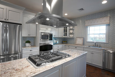 Foto de cocina clásica cerrada con fregadero encastrado, armarios con paneles con relieve, encimera de granito y electrodomésticos de acero inoxidable
