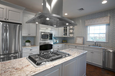 This is an example of a traditional enclosed kitchen in New York with a built-in sink, raised-panel cabinets, granite worktops and stainless steel appliances.