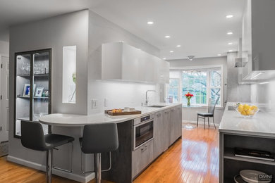 Example of a small minimalist galley medium tone wood floor and multicolored floor eat-in kitchen design in Boston with an undermount sink, flat-panel cabinets, gray cabinets, quartz countertops, multicolored backsplash, stone slab backsplash, paneled appliances and white countertops