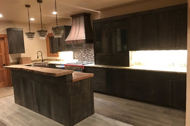 Example of a mid-sized mountain style u-shaped porcelain tile and gray floor open concept kitchen design in Denver with a farmhouse sink, recessed-panel cabinets, dark wood cabinets, wood countertops, multicolored backsplash, matchstick tile backsplash, stainless steel appliances and an island
