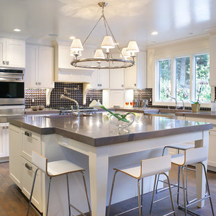 Large contemporary eat-in kitchen appliance - Example of a large trendy u-shaped eat-in kitchen design in Las Vegas with stainless steel appliances, concrete countertops, a farmhouse sink, shaker cabinets, white cabinets, multicolored backsplash and an island