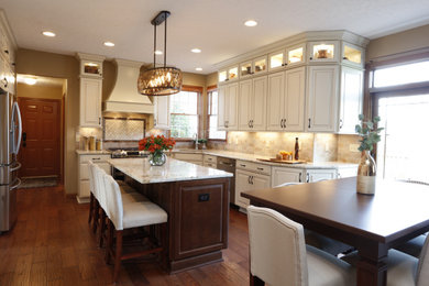 Large u-shaped medium tone wood floor and brown floor eat-in kitchen photo in Cleveland with an undermount sink, raised-panel cabinets, white cabinets, granite countertops, beige backsplash, porcelain backsplash, stainless steel appliances, an island and beige countertops