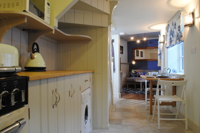 Imagen de cocina costera con encimera de madera, salpicadero de madera, suelo de baldosas de porcelana y suelo beige