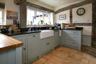 This is an example of a large country kitchen in Surrey with shaker cabinets, blue cabinets, granite worktops, white splashback, beige floors and black worktops.