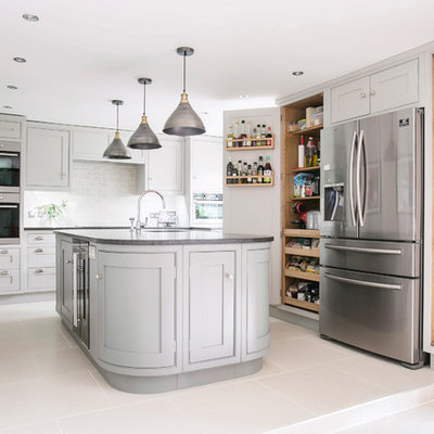 Example of a mid-sized classic u-shaped ceramic tile and white floor eat-in kitchen design in Kent with a farmhouse sink, gray cabinets, granite countertops, an island, white backsplash, shaker cabinets, subway tile backsplash, paneled appliances and black countertops