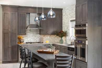 Inspiration for a mid-sized transitional l-shaped porcelain tile and gray floor eat-in kitchen remodel in New York with an undermount sink, shaker cabinets, gray cabinets, multicolored backsplash, glass sheet backsplash, stainless steel appliances, an island, gray countertops and granite countertops