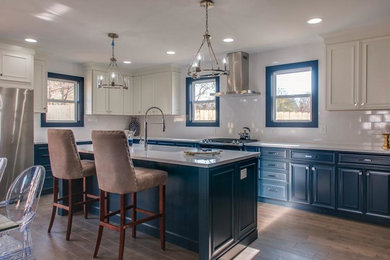 Example of a large transitional single-wall medium tone wood floor and brown floor kitchen design in Nashville with an undermount sink, recessed-panel cabinets, blue cabinets, marble countertops, white backsplash, ceramic backsplash, stainless steel appliances, an island and white countertops