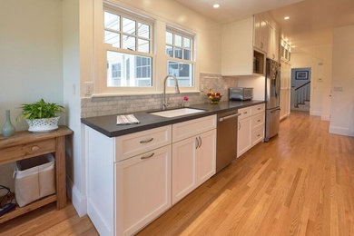Example of a mid-sized transitional galley medium tone wood floor and brown floor eat-in kitchen design in San Francisco with an undermount sink, recessed-panel cabinets, white cabinets, quartz countertops, gray backsplash, porcelain backsplash, stainless steel appliances, no island and gray countertops