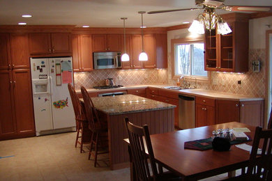 Foto på ett retro kök och matrum, med en dubbel diskho, släta luckor, skåp i mellenmörkt trä, granitbänkskiva, stänkskydd i keramik, rostfria vitvaror, klinkergolv i keramik och en köksö