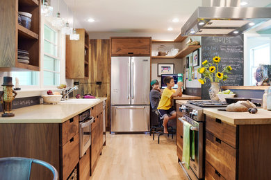 Example of a small eclectic galley light wood floor eat-in kitchen design in Other with a drop-in sink, flat-panel cabinets, dark wood cabinets, quartz countertops, black backsplash, stainless steel appliances and a peninsula