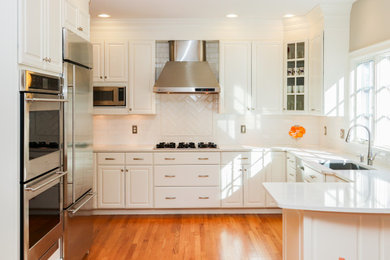 ボストンにある高級な広いトラディショナルスタイルのおしゃれなキッチン (アンダーカウンターシンク、落し込みパネル扉のキャビネット、白いキャビネット、珪岩カウンター、白いキッチンパネル、サブウェイタイルのキッチンパネル、シルバーの調理設備、無垢フローリング、茶色い床、白いキッチンカウンター) の写真