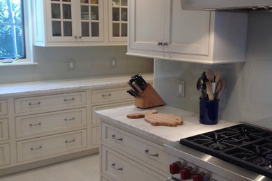 Bild på ett avskilt, mellanstort vintage u-kök, med en undermonterad diskho, skåp i shakerstil, vita skåp, bänkskiva i kvartsit, grått stänkskydd, stänkskydd i sten, rostfria vitvaror, travertin golv och en halv köksö