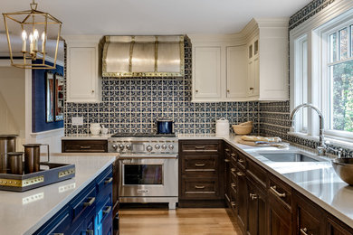 Example of a mid-sized classic l-shaped light wood floor and brown floor enclosed kitchen design in Boston with an undermount sink, recessed-panel cabinets, blue cabinets, quartz countertops, blue backsplash, porcelain backsplash, stainless steel appliances, an island and gray countertops