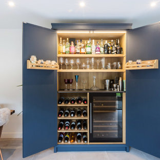 Inspiration for a large industrial l-shaped eat-in kitchen in Essex with a double-bowl sink, shaker cabinets, blue cabinets, solid surface benchtops, multi-coloured splashback, ceramic splashback, black appliances, porcelain floors, with island, grey floor and black benchtop.