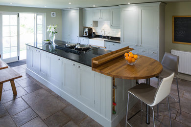 Photo of a classic kitchen/diner in Devon with a double-bowl sink, shaker cabinets, blue cabinets, granite worktops, white splashback, ceramic splashback, integrated appliances and an island.